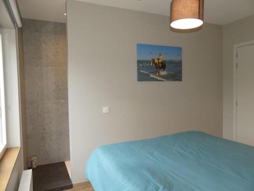 a bedroom with a blue bed and a picture on the wall at vakantiehuis Le Libr-air in Koksijde