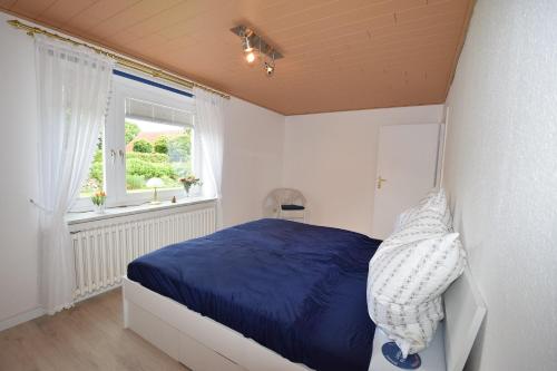 a bedroom with a blue bed and a window at Haus Steinkamp in Blekendorf