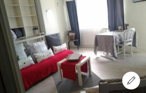 un salon avec un canapé rouge et une table dans l'établissement Un nid douillet en ville, à Épinal