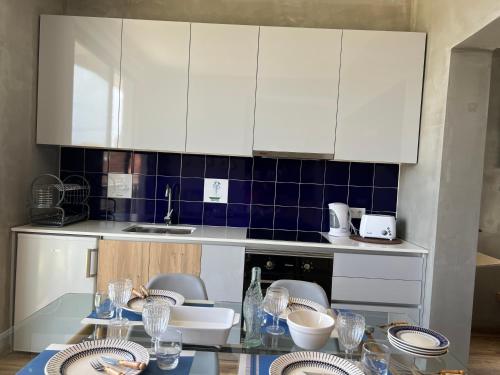 a kitchen with white cabinets and a table with plates at Caniçal houses - Madeira in Caniçal