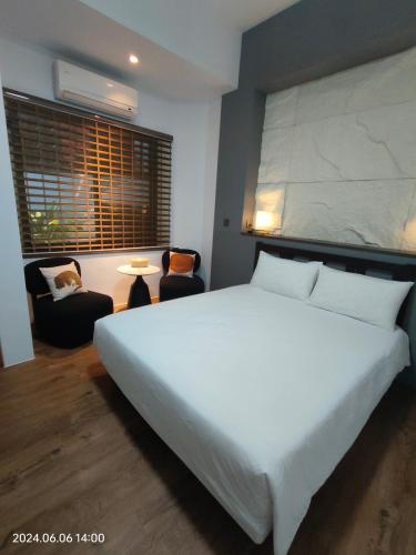 a bedroom with a large white bed and chairs at 小時公館城西 in Yuli