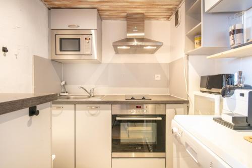 une cuisine avec des armoires blanches et un four à plaques de cuisson dans l'établissement Le Refuge - Appt vue montagne, à Chamrousse