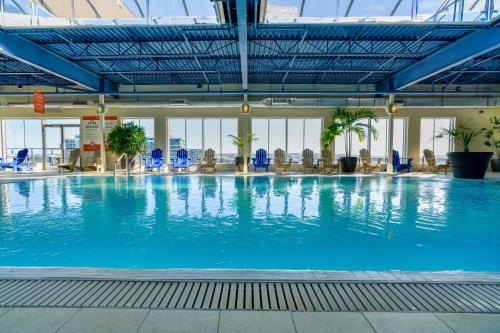 a large swimming pool in a building with blue chairs at Hôtel Must Aéroport de Québec par JARO in Quebec City