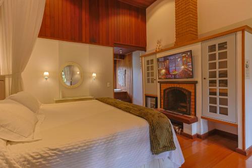 a bedroom with a large bed and a fireplace at Pousada Cantos e Contos in Monte Verde
