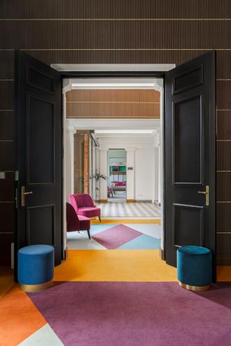 an open door into a living room with a pink chair at Room Mate Luca, Florence in Florence