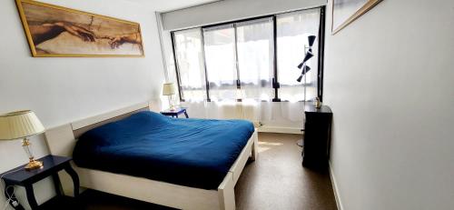 une chambre avec un lit bleu et une fenêtre dans l'établissement Village Faidherbe Appartement d'Angle Moderne, à Paris