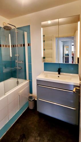 une salle de bain avec un lavabo, une baignoire et un miroir dans l'établissement Village Faidherbe Appartement d'Angle Moderne, à Paris
