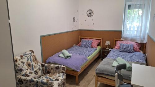 two beds in a room with a couch and a chair at Roli Bácsi Háza in Tapolca