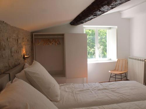 une chambre avec un lit, une fenêtre et une chaise dans l'établissement Le Moulin, avec parc, piscine, au cœur du village, à Villegly
