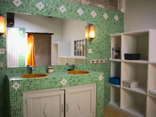 - une salle de bains carrelée de vert avec deux lavabos et un miroir dans l'établissement Le Moulin, avec parc, piscine, au cœur du village, à Villegly