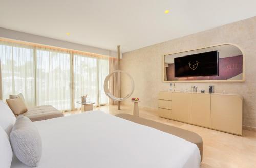 a bedroom with a large bed and a flat screen tv at The Eden by Desire Riviera Maya All Inclusive - Couples Only in Puerto Morelos