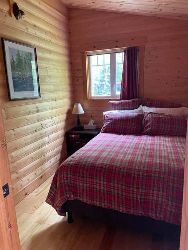 a bedroom with a bed in a log cabin at Le Refuge au Mont Comi in Saint-Gabriel