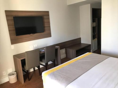 a bedroom with a bed and a desk and a tv at Recife Mar Flats Hotel in Recife