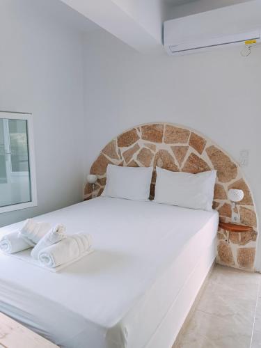 a white bed in a room with a stone wall at The Life Suites in Limniónas