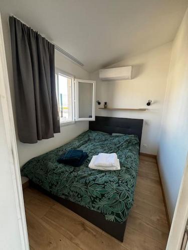 - une petite chambre avec un lit et une couverture verte dans l'établissement ROOFTOP vue mer, à Vallauris