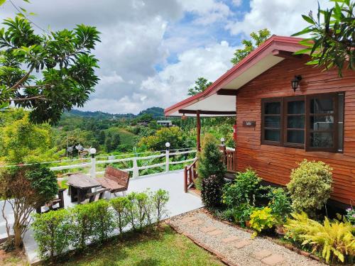 a wooden house with a table and a bench at บ้านสุขอรุณ เขาค้อ Baan Sook A Roon KhaoKho in Khao Kho