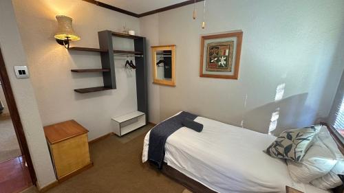 a small bedroom with a bed and a shelf at White River Selfcatering at Greenway woods House no 9 in White River
