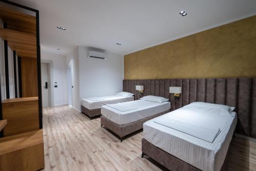 a bedroom with two beds and a wall at Edva Resort in Vlorë
