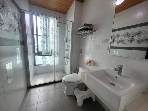 a white bathroom with a toilet and a sink at Come Home Travel in Tainan