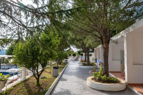 a walkway with trees and benches on the side of a building at Edva Resort in Vlorë