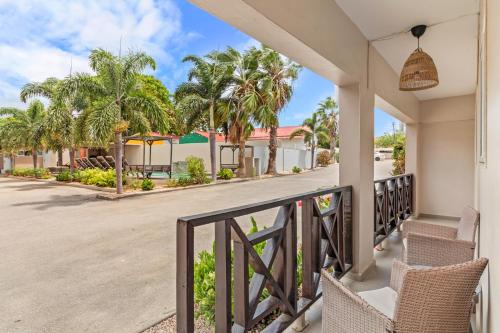 a balcony with chairs and palm trees on a house at Curadise Living in Willemstad