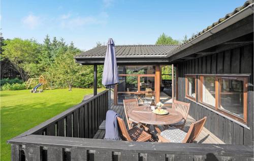 a deck with a table and chairs and an umbrella at Holiday Home Rønnevej Fjerritslev Ix in Fjerritslev