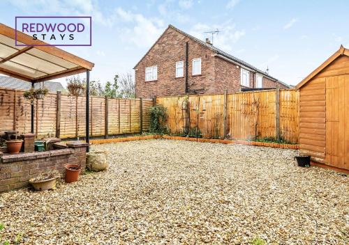 a backyard with a wooden fence and a house at Cosy 3-Bedroom Serviced House with Free Fast WiFi and Parking for 2 Cars By Redwood Stays in Camberley