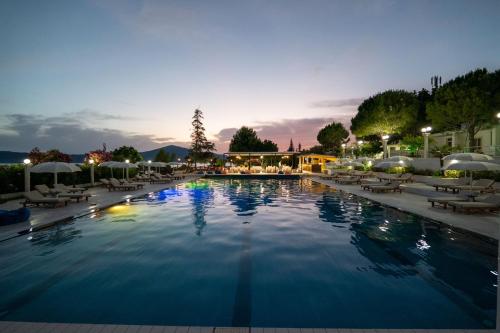 a large swimming pool with lounge chairs and umbrellas at Edva Resort in Vlorë