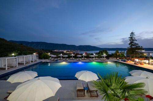 a swimming pool with umbrellas and chairs and a resort at Edva Resort in Vlorë
