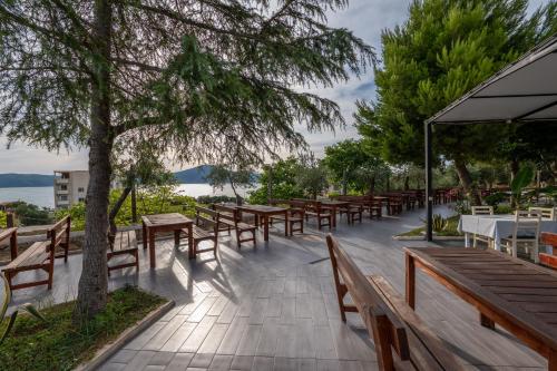 a row of wooden tables and benches and a tree at Edva Resort in Vlorë