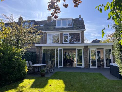 a house with glass doors and a yard at Villa Cosy Central incl Jacuzzi Near trainstation, beach and city in Heemstede