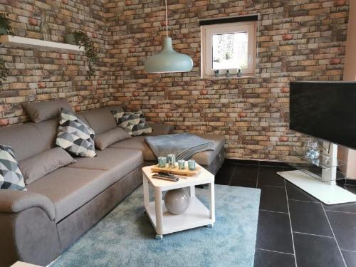 a living room with a couch and a brick wall at Ferienappartement Marburg Giessen in Hachborn