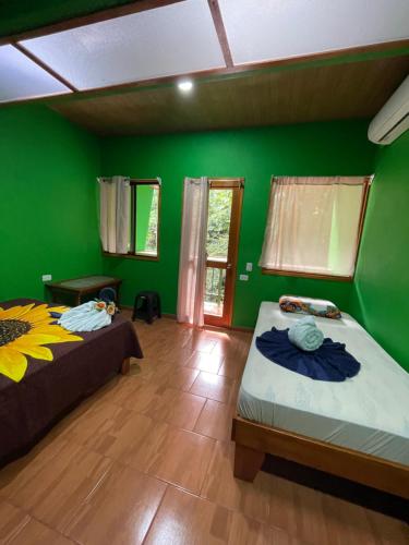 two beds in a room with green walls at Ceiba lodge in Drake