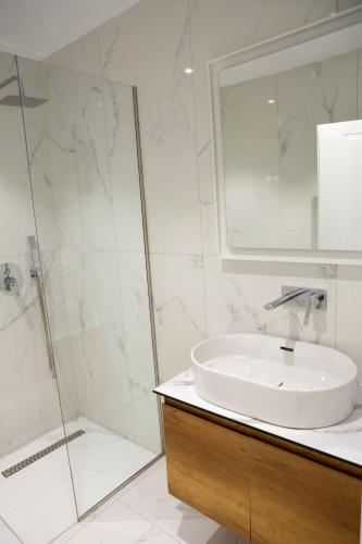 a white bathroom with a sink and a shower at Sofia Apartments in Sarandë