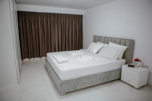 a bedroom with a large bed with white sheets and pillows at Sofia Apartments in Sarandë