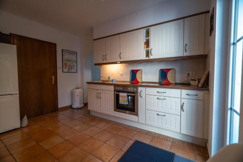 a kitchen with white cabinets and a tile floor at Jachthuus in Brilon