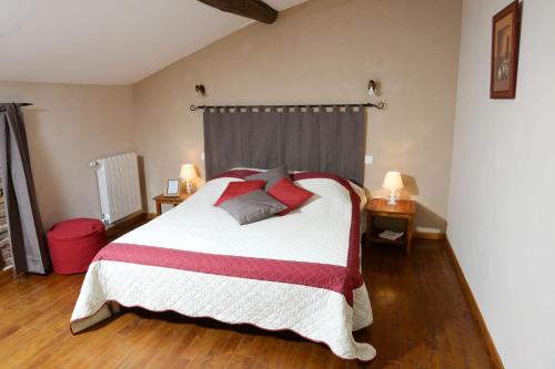 a bedroom with a large bed with red pillows at La Ferme de Menoun in Thil