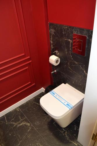 a bathroom with a toilet and a red wall at Park Gate apartment in Chernivtsi