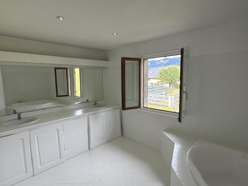 une salle de bain blanche avec deux lavabos et une fenêtre dans l'établissement Peaceful Retreat Between Lake and Mountain Charming House Near Annecy and Aix-les-Bains, à Chainaz-les-Frasses