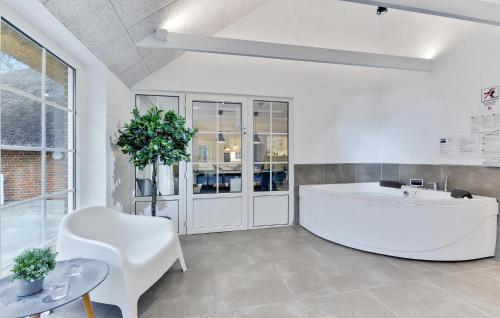 a large white room with a tub and a chair at Lovely Home In Ulfborg With Sauna in Ulfborg