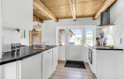a kitchen with white cabinets and black counter tops at Beautiful Home In Ulfborg With Kitchen in Øhuse