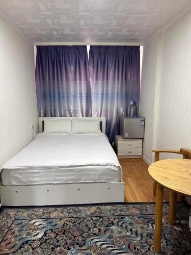 a bedroom with a white bed and a table at Camel Track Guesthouse and Tour Operator LLC in Ulaanbaatar
