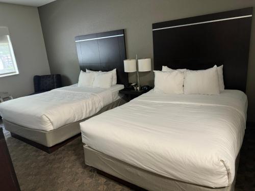 two beds in a hotel room with white sheets at Comfort Inn Huntington near University area in Huntington