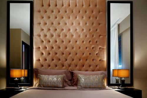 a bedroom with a large padded headboard and two mirrors at Minho Valley in Caminha