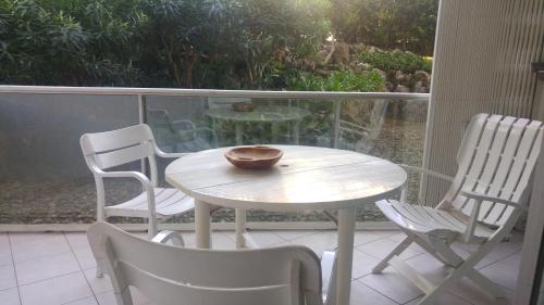 une table blanche et des chaises sur un balcon avec un bol dessus dans l'établissement Gautier Jean, à Cannes