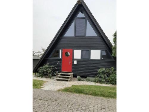 a black and red house with a red door at Ferienhaus in Fedderwardersiel mit Terrasse und Garten in Butjadingen