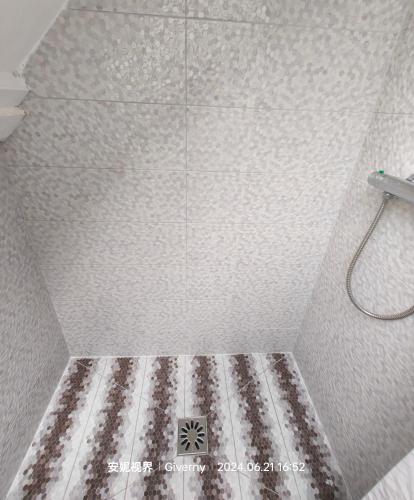 a bathroom with a shower with a tile floor at Le Coin des Artistes in Giverny