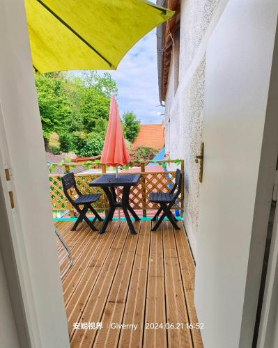 a patio with a table and chairs on a deck at Le Coin des Artistes in Giverny