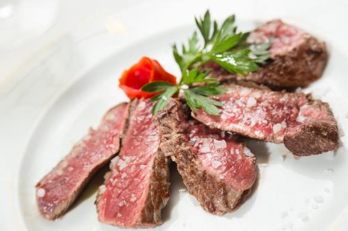 a plate of meat with a red flower on it at Hotel Milton Rimini in Rimini