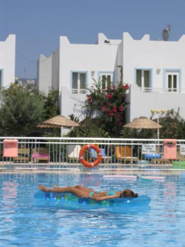 a person laying on a raft in a swimming pool at Hotel Bağevleri in Gümbet